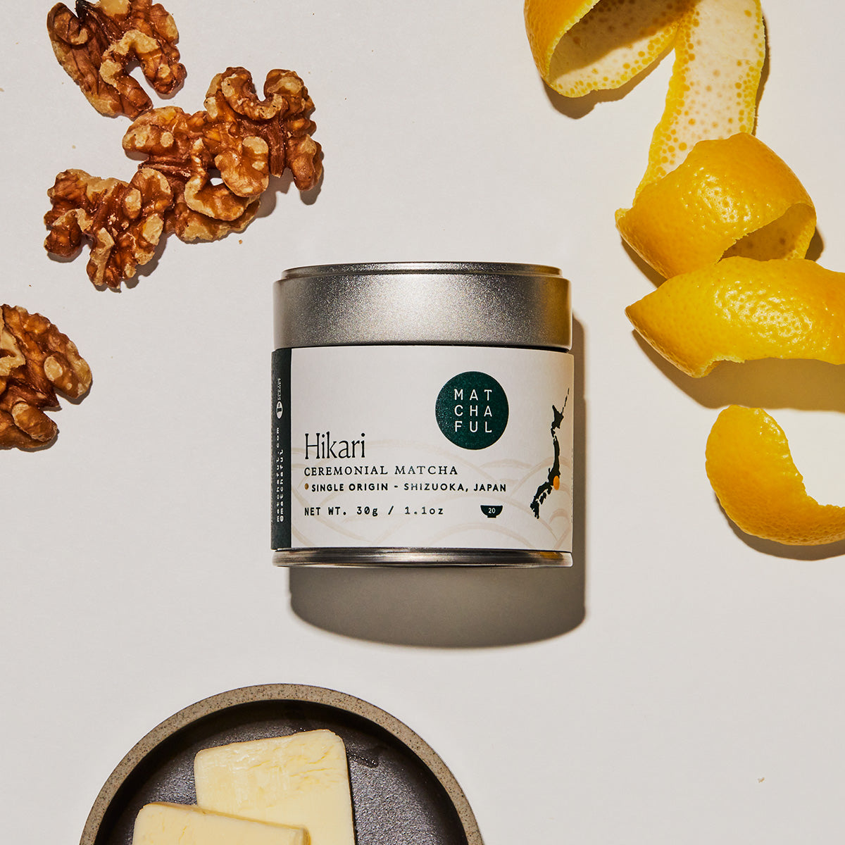 Matchaful Hikari Ceremonial Matcha tin surrounded by tasting notes of walnuts, lemon, and butter